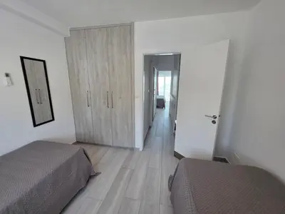 a bedroom with two beds and a door to a hallway at Protaras Ayios Elias Maisonette in Protaras