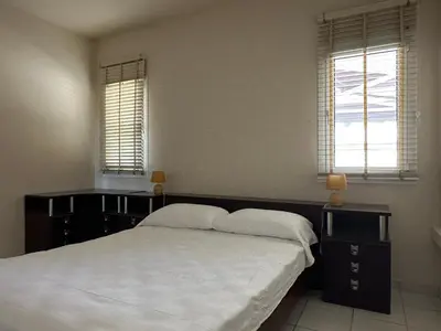 a bedroom with a large bed and two windows at White House with Garden and BBQ in Strovolos in Nicosia