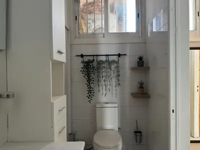a white bathroom with a toilet and a window at White House with Garden and BBQ in Strovolos in Nicosia