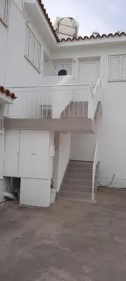 a white house with a staircase and a stair case at Quiet Top Floor One Bedroom Apartment in Pyla Near Beach in Voroklini