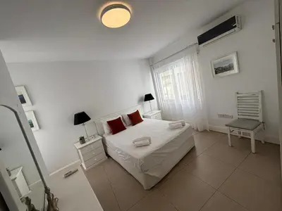 a white bedroom with a bed and a window at Modern 2BR Apartment 70m from Finikoudes beach in Larnaka