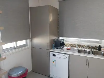 a kitchen with white cabinets and a sink and windows at Black Swan Villa in Pervolia