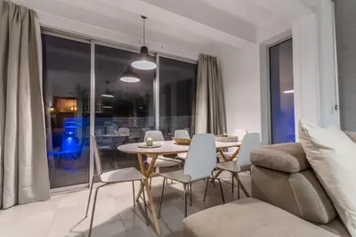 a living room with a table and chairs and a couch at Black Swan Villa in Pervolia