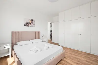 a white bedroom with a large bed and white cabinets at Nautical Club Penthouse Apartments in Larnaka