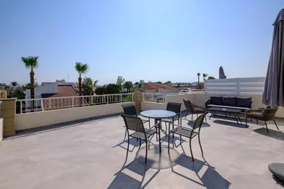 a patio with a table and chairs on a roof at Nautical Club Penthouse Apartments in Larnaka
