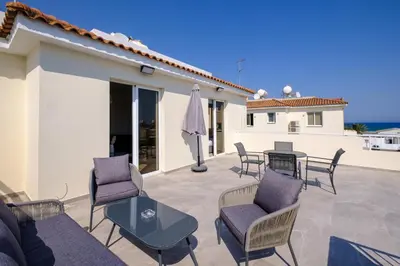 a patio with chairs and a table and a house at Nautical Club Penthouse Apartments in Larnaka