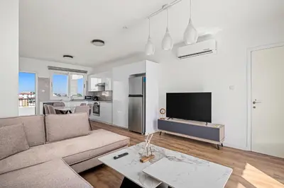 a living room with a couch and a tv at Nautical Club Penthouse Apartments in Larnaka