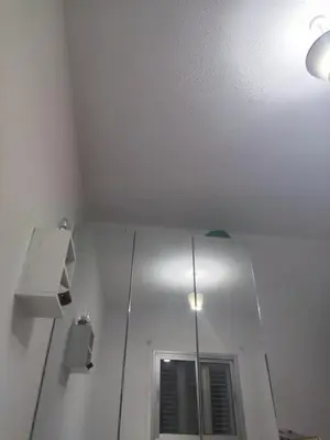 a white room with a mirror and a ceiling at A separate room with a shared bathroom and 50 meters from the sea in Zygi