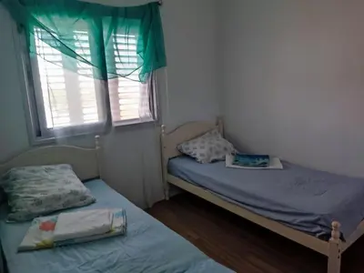 a small bedroom with two beds and a window at A separate room with a shared bathroom and 50 meters from the sea in Zygi