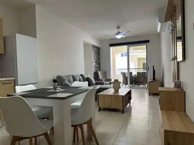 a kitchen and living room with a table and chairs at Majestic Gardens 10 minutes from Larnaka Airport in Tersephanou