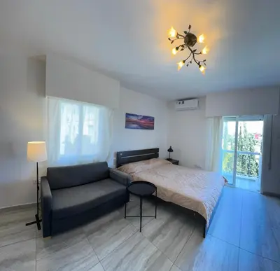 a bedroom with a bed and a couch and a chandelier at Уютные Апартаменты с Балконом in Limassol