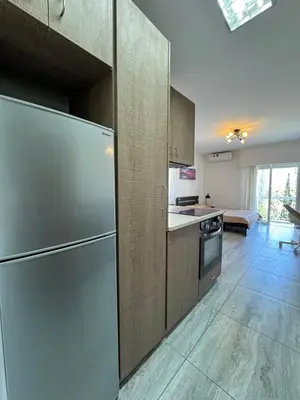 a kitchen with a stainless steel refrigerator and a living room at Уютные Апартаменты с Балконом in Limassol