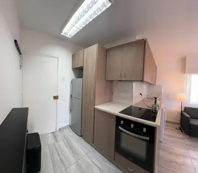 a kitchen with wooden cabinets and a stove top oven at Уютные Апартаменты с Балконом in Limassol