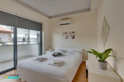 a bedroom with a white bed and a large window at Dios Ponte 102 Beachfront in Larnaka
