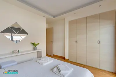 a bedroom with a large white bed and a mirror at Dios Ponte 102 Beachfront in Larnaka