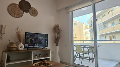 a living room with a television and a balcony with a table at STAY Miracle Apartment in Larnaka