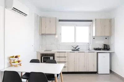 a kitchen with wooden cabinets and a table and chairs at Napa Heights in Ayia Napa