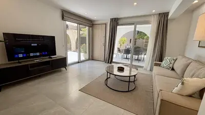 a living room with a couch and a tv and a table at Kantara Garden Apt by TrulyCyprus in Limassol
