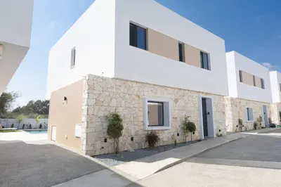a white building with a stone wall at Ayia Napa Orea Villa OR2 in Ayia Napa