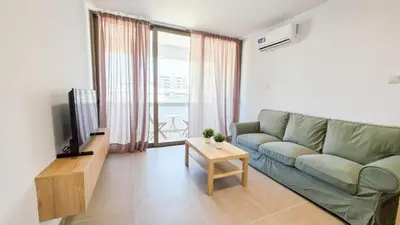 a living room with a green couch and a television at Olive Dunes Stay in Larnaka