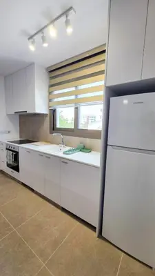 a kitchen with white cabinets and a sink and a window at Olive Dunes Stay in Larnaka
