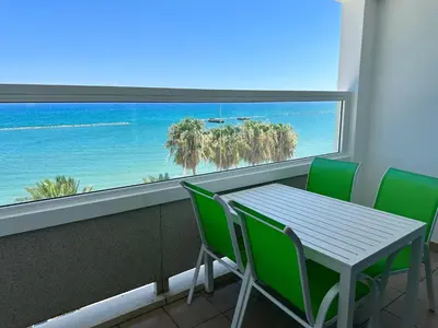 a table and chairs in a room with a view of the ocean at GARNET Beach Apartment in Voroklini
