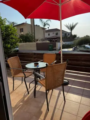 a patio table and chairs with a red umbrella at Sunflight Apt 01B One Bedroom Apt in Larnaka