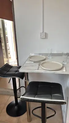 a table with two chairs and two plates on it at Sunflight Apt 01B One Bedroom Apt in Larnaka