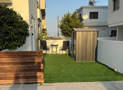 a small backyard with a wooden fence and grass at Sunflight Apt 01B One Bedroom Apt in Larnaka