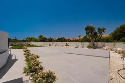a concrete driveway with a fence and palm trees at Exclusive 7-Bdr Villa with Panoramic Views & Saltwater swimming pool! in Ayia Napa