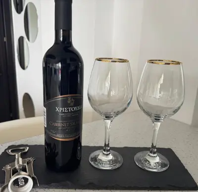 a bottle of wine and two wine glasses on a counter at Blue Tulip - Strovolos in Kato Lakatamia