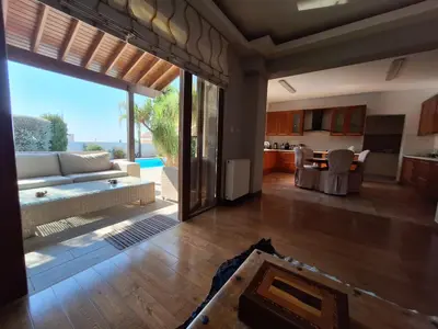 a living room with a couch and a table and a kitchen at Live in landlord guest house panthea in Limassol