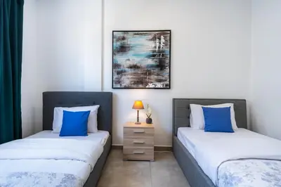 two twin beds in a room with blue pillows at Invictus 2-Bedroom Apartment in Larnaka