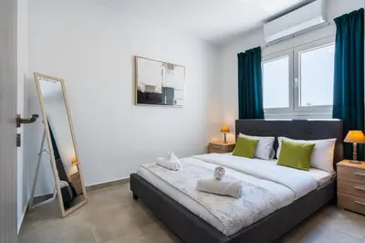 a bedroom with a bed with green curtains and a mirror at Invictus 2-Bedroom Apartment in Larnaka