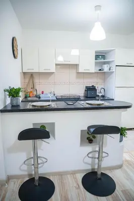 a kitchen with two bar stools in front of a counter at ONAR mackenzie 1 in Larnaka