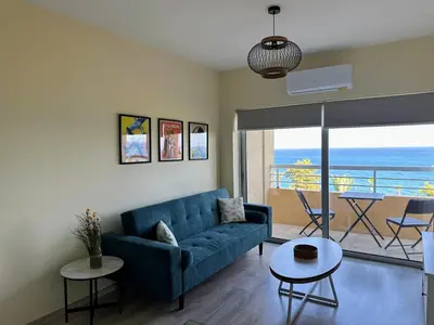 a living room with a blue couch and a view of the ocean at Seaview Apartment in Limassol in Limassol