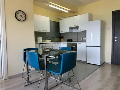 a kitchen with a table and chairs and a clock at Seaview Apartment in Limassol in Limassol