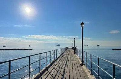 a person walking on a wooden pier with the ocean at Oceanside Living - Modern 1 bedroom in Limassol