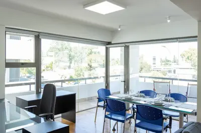 a dining room with blue chairs and tables and windows at Cosy & Bright European Uni Apt in Strovolos