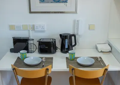 a table with two chairs and two plates and a coffee maker at Cosy & Bright European Uni Apt in Strovolos