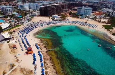 an aerial view of a beach with umbrellas and a swimming pool at Nissi Pearl Seaside Residence in Ayia Napa