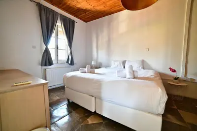 a bedroom with a large white bed and a window at Laouri Traditional 2-Bedroom in Kalopanayiotis in Kalopanayiotis
