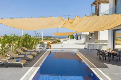 a patio with a pool and chairs and a table at Seaside Emerald in Paralimni