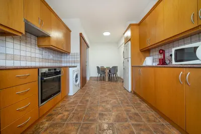 a kitchen with wooden cabinets and a tile floor at Cozy 3 bedroom flat city center in Nicosia
