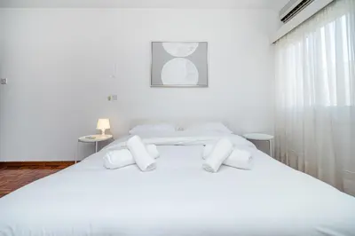 a white bedroom with two beds with white pillows at Cozy 3 bedroom flat city center in Nicosia