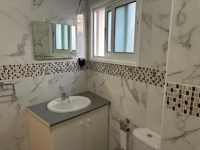 a white bathroom with a sink and a mirror at Michaela's place in Aglantzia