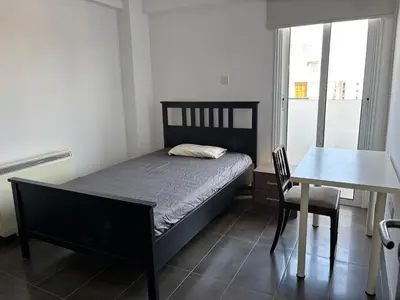 a bedroom with a bed and a table and a desk at Michaela's place in Aglantzia