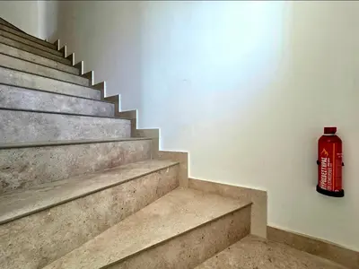 a red fire extinguisher sitting on the wall next to stairs at Larnaca Villa in Sophtadhes