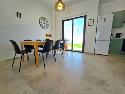 a dining room with a table and black chairs at Larnaca Villa in Sophtadhes