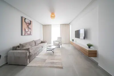 a living room with a couch and a tv at Serene Gardens 2BR w Pool in Livadhia